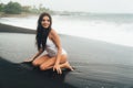 Side view of sexy girl in bikini spends time on black sand beach. Young woman with long hair posing outdoor Royalty Free Stock Photo