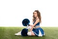View of sexy happy cheerleader girl in blue uniform with pompoms on green field isolated on white