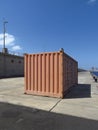 Side view of shipping container in industrial dock, and blue sky. Rectangular container for the transport of goods waiting for Royalty Free Stock Photo