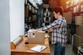 Side view of a short haired female warehouse worker packing a cardboard box Royalty Free Stock Photo