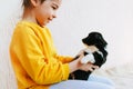 Side view shot of the happy child playing at home with little dog. Pretty little girl cares about the puppy. Kid playing her pet Royalty Free Stock Photo