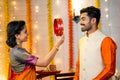 Side view shot of indian wife looking husband face through sieve during karva chauth festival at home - concept of