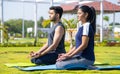 Side view shot of Indian young couple doing yoga or meditation at park during morning - concept of mindfulness, training