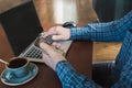 Side view shot of a man`s hands using smart phone and laptop sitting at wooden table with cup of coffee. Close up. Royalty Free Stock Photo