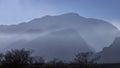 Side view of the silhouettes of mountain ranges in the fog.