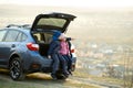 Side view of sister and brother sitting in car trunk and looking on nature. Concept of resting on fresh air with family Royalty Free Stock Photo