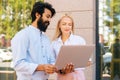 Side view of skilled bearded business man explaining and teaching to young attractive blonde female colleague working Royalty Free Stock Photo