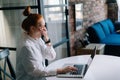 Side view of sleepy redhead young woman yawning while working on laptop computer sitting at table Royalty Free Stock Photo