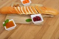 Side view of sliced french bread and three bowl of jam