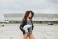 Side view of slim brunette biker girl in bodysuit and leather jacket with safety bike helmet Royalty Free Stock Photo