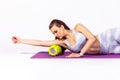 Side view slim sportive woman in white top and tights massaging hands and relieving tension using fitness roller lying on yoga mat Royalty Free Stock Photo