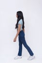 Side view of a slim trans woman walking slowly like a model. Sauntering wearing a light blue printed shirt and jeans. Whole body