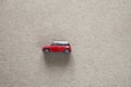 Side view of small bright red metal simple child toy car on light beige canvas cloth copy space background