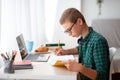 Side view of smart schooler doing homework at room