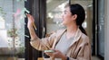 Side view smiling asian woman putting sticky notes on glass window in creative office Royalty Free Stock Photo