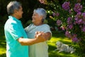 Side view of smiling biracial senior couple looking at each other while dancing by flowers in park Royalty Free Stock Photo