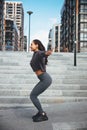 Joyful athlete with Afro bunches squatting outdoors Royalty Free Stock Photo