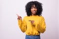 Side view of smiling curly african woman pointing away and looking at the camera over gray background Royalty Free Stock Photo