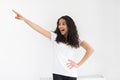 Side view of smiling curly woman pointing away and looking at the camera over white background Royalty Free Stock Photo