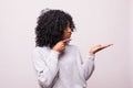 Smiling curly african woman pointing away and looking at the camera over white background Royalty Free Stock Photo