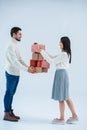 side view of smiling multicultural couple holding stack of wrapped christmas gifts