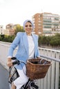 Side view of a muslim woman standing with her bike on a footbridge looking at camera Royalty Free Stock Photo