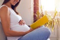 Smiling pregnant woman sitting on sofa and reading book Royalty Free Stock Photo