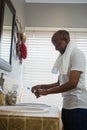 Side view of smiling senior man holding toothpaste and brush in bathroom Royalty Free Stock Photo