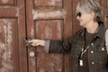 Side view of a smiling senior woman with gray hair in front of an old red door closed by a padlock. Traditional rustic Spanish Royalty Free Stock Photo