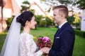 Side view of smiling wedding couple holding bouquet at lawn