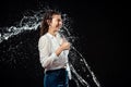 side view of smiling woman in white shirt showing thumb up while swilled with water