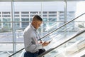 Young businessman using smartphone on an escalator Royalty Free Stock Photo