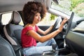 Happy black woman sitting in car and using navigator in daylight