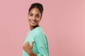 Side view of smiling young african american woman girl in green sweatshirt posing isolated on pastel pink background Royalty Free Stock Photo