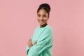 Side view of smiling young african american woman girl in green sweatshirt posing isolated on pastel pink background Royalty Free Stock Photo