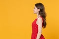 Side view of smiling young brunette woman girl in red summer dress posing isolated on yellow background studio portrait Royalty Free Stock Photo