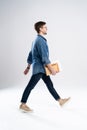 Side view of a smiling young casual man walking, student with book ang notes on white background. Royalty Free Stock Photo