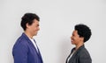 Side view of smiling young colleague with afro hairstyle looking at each other over white background Royalty Free Stock Photo