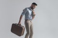 Side view of smiling young guy with jacket over shoulder holding briefcase Royalty Free Stock Photo