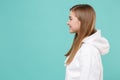 Side view of smiling young woman girl in casual white hoodie posing isolated on blue turquoise background studio Royalty Free Stock Photo