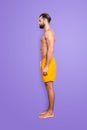 Side view snap full size fullbody portrait of attractive strong lifeguard with stubble, modern hairstyle in yellow