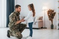 Side view. Soldier in uniform is at home with his little daughter