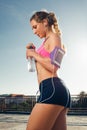 side view of sportswoman in earphones with smartphone in running armband case closing bottle of water