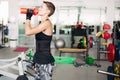 Side view of sporty woman drinking water from pink bootle.