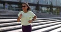 Side view of sporty young mixed-race woman running on sidewalk in morning. Royalty Free Stock Photo