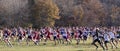 Side view of the start of a high school cross country race on a field with atumn colored trees Royalty Free Stock Photo