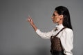 View of steampunk young woman in white blouse gesturing on grey