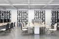 Side view on stylish open space office with modern computers on light wooden work tables, light chairs on concrete glossy floor Royalty Free Stock Photo