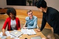 Side view of successful business team leader standing surrounded by diverse colleagues, confidently looking to staff Royalty Free Stock Photo