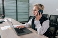 Side view of successful middle-aged businesswoman talking on phone while working typing on laptop sitting at office desk Royalty Free Stock Photo